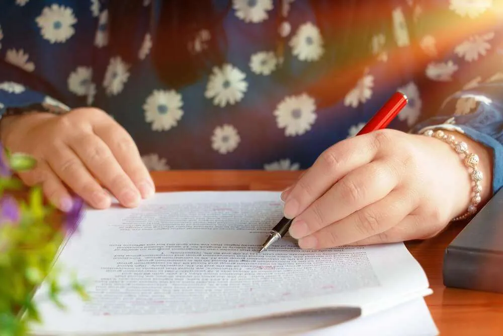 A woman annotates a piece of paper with a red pen