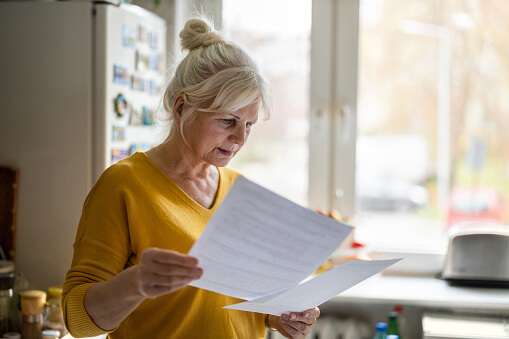Woman in a yellow jumper reading printed A4 pages.